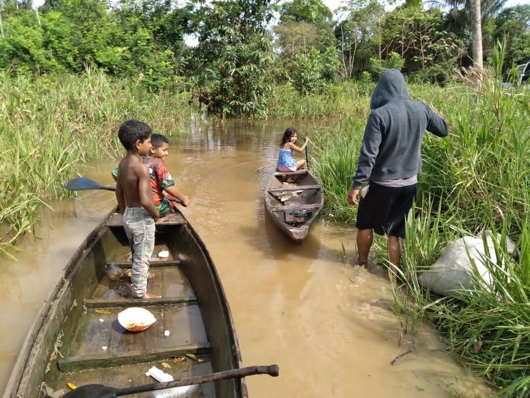 três criança em uma canoa